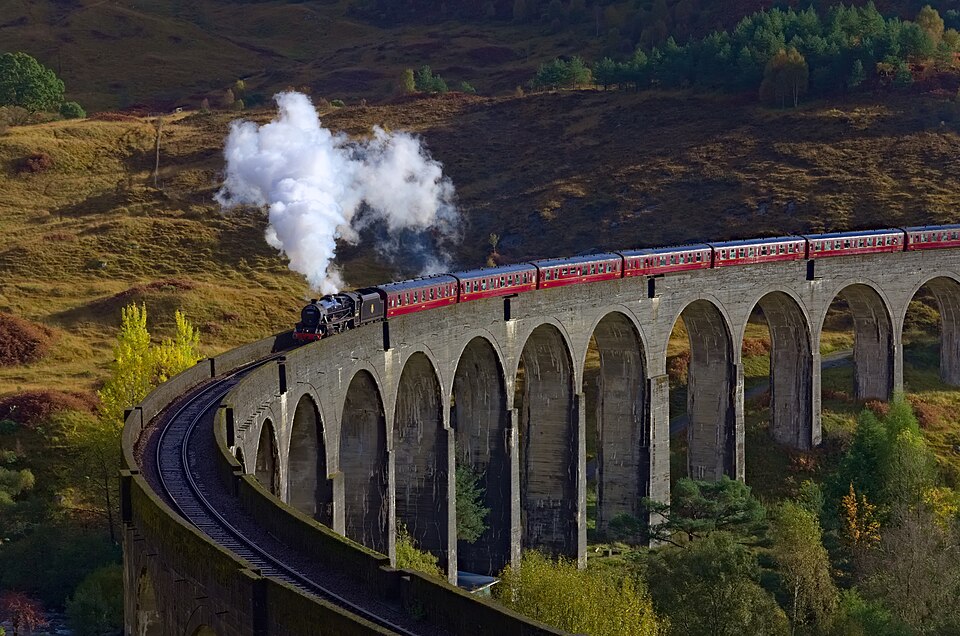 A steam train crossing the curved Glenfinnan Viaduct in the Scottish Highlands